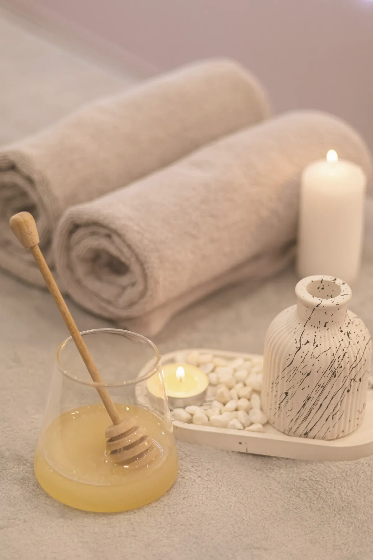 Rolled towels, a candle and honey